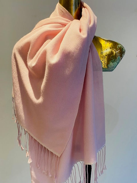 A pink pashmina scarf with fringe trim displayed on a mannequin.