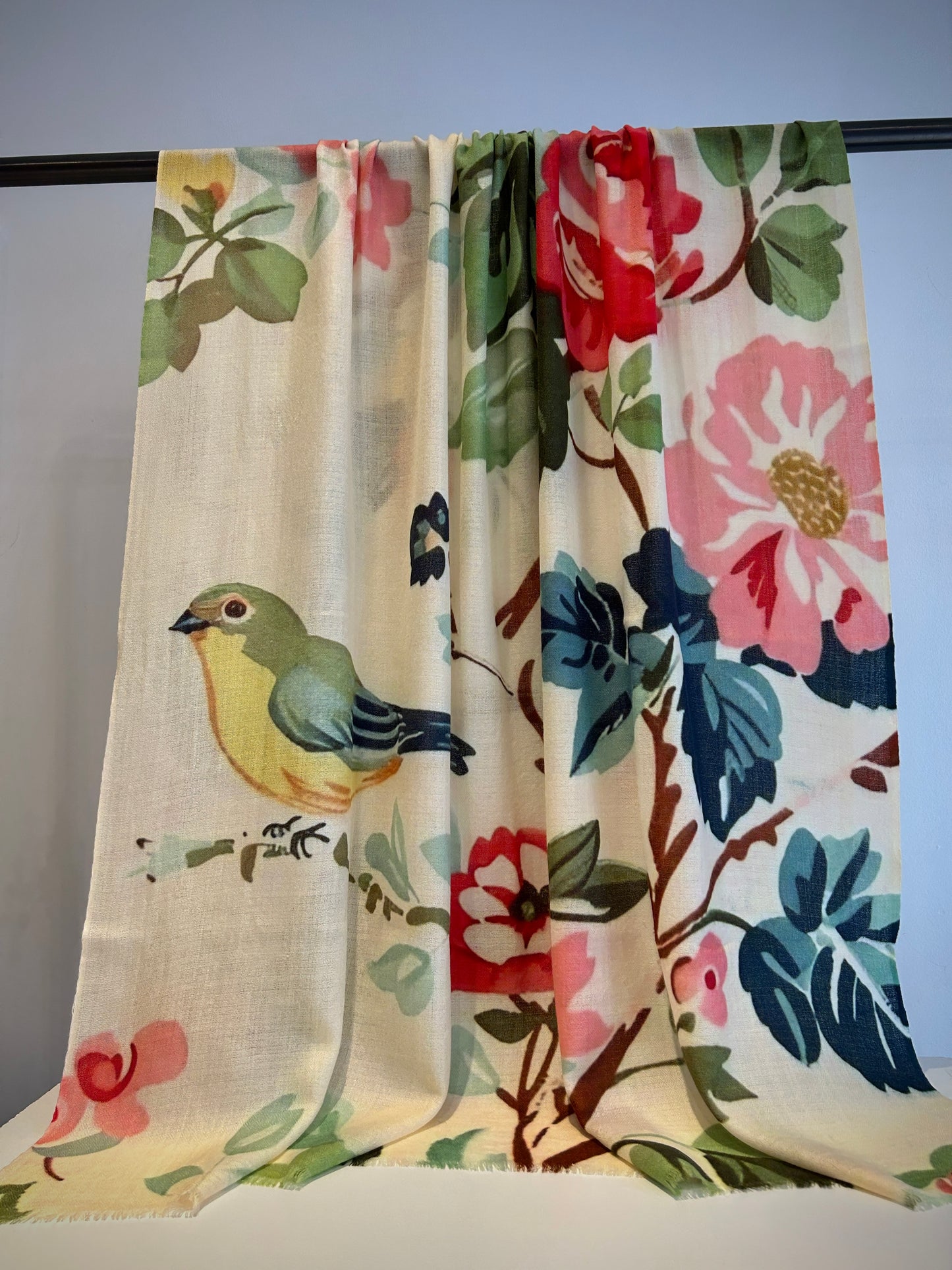 Floral and bird-themed curtain with colorful design on a rod against a light background