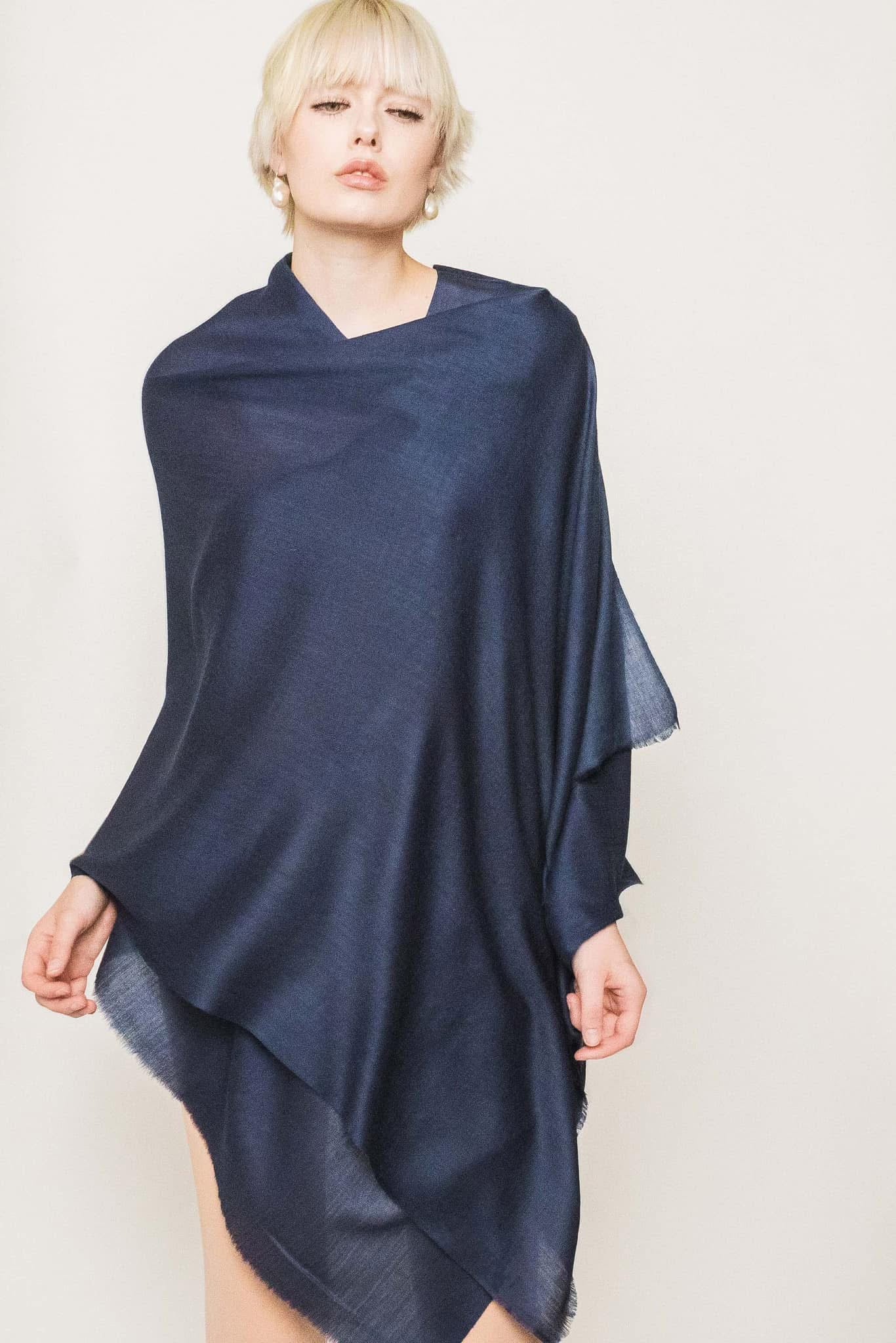 Woman wearing a navy blue shawl against a plain background